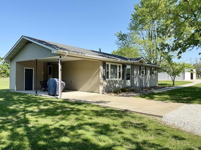 rear view of house with a yard, a patio area, driveway, and a carport