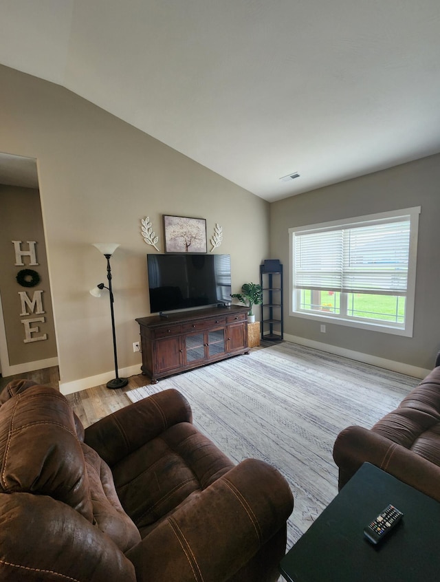living area with lofted ceiling, baseboards, visible vents, and wood finished floors
