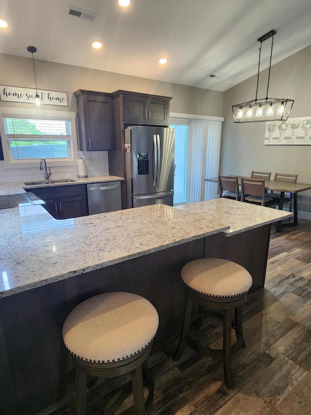 kitchen featuring light stone counters, appliances with stainless steel finishes, a sink, and dark wood-type flooring