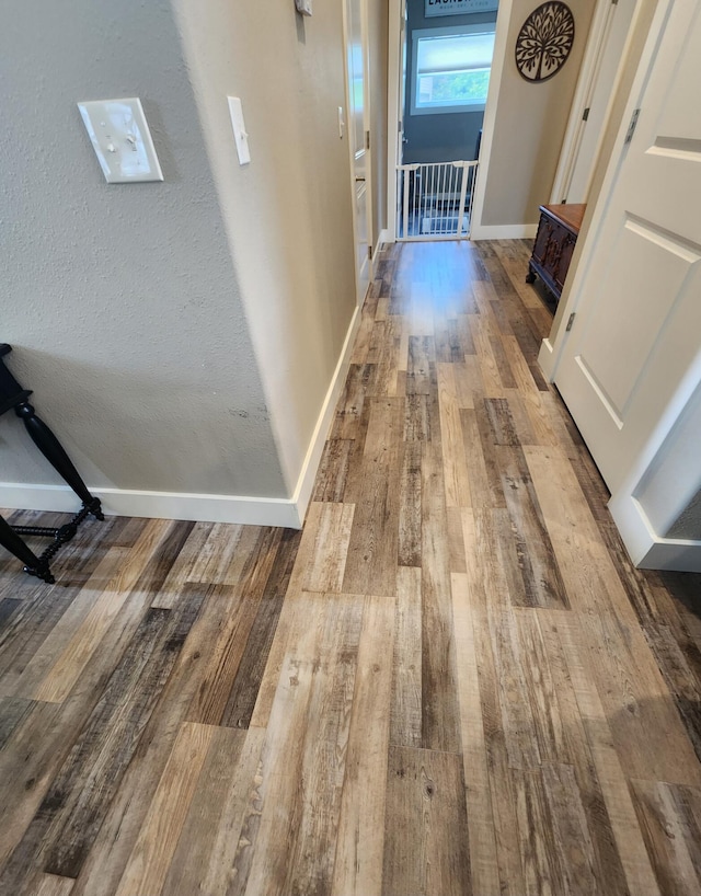 corridor with baseboards and hardwood / wood-style floors