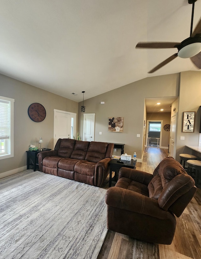 living room with baseboards, wood finished floors, a ceiling fan, and lofted ceiling
