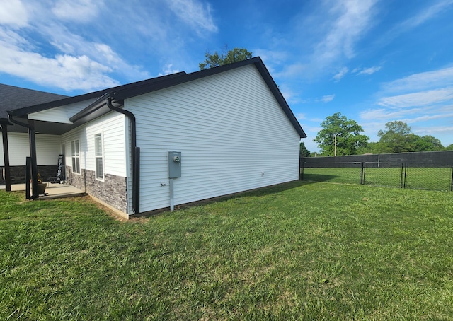 view of home's exterior with stone siding, a yard, fence, and a patio area