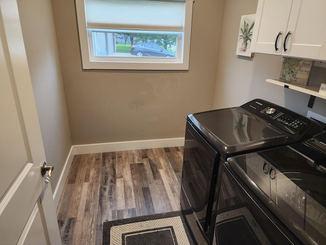 laundry area featuring washing machine and clothes dryer, cabinet space, baseboards, and wood finished floors