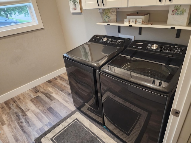 laundry area featuring baseboards, independent washer and dryer, cabinet space, and wood finished floors