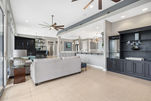 living area with light tile patterned floors, baseboards, recessed lighting, and ceiling fan with notable chandelier