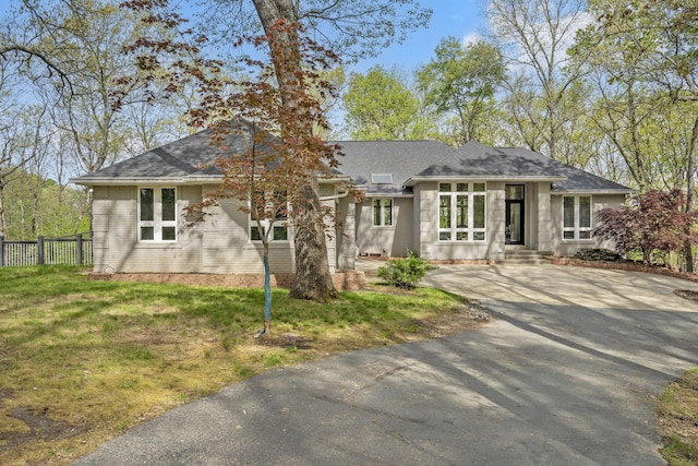 view of front of house featuring a shingled roof, fence, a front yard, and aphalt driveway