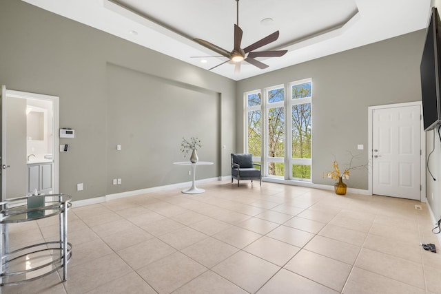 sitting room with light tile patterned floors, baseboards, a ceiling fan, and a high ceiling