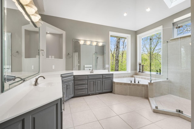 bathroom featuring a garden tub, a sink, a skylight, two vanities, and tile patterned flooring