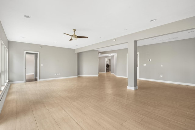 unfurnished living room featuring ceiling fan, baseboards, and light wood-style floors