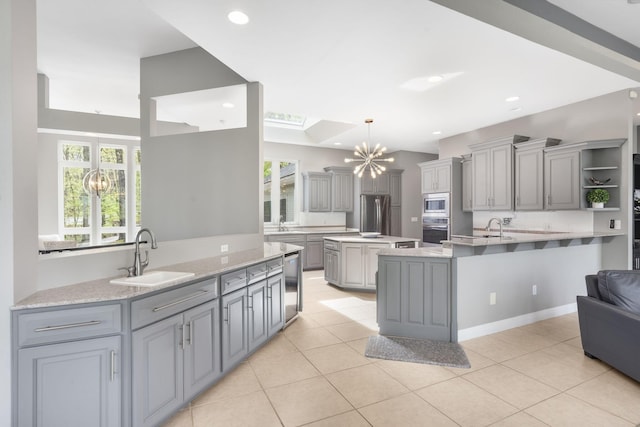 kitchen with a notable chandelier, gray cabinets, stainless steel appliances, and a sink