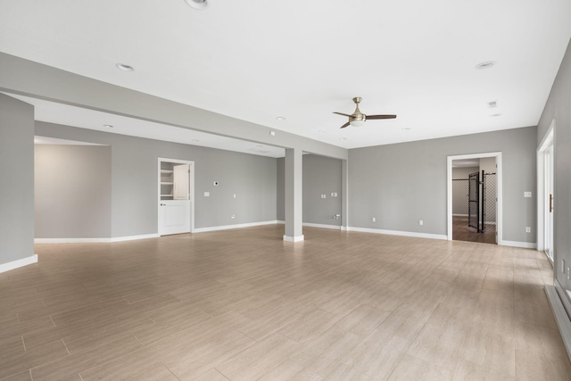 unfurnished room featuring baseboards, a ceiling fan, and light wood-style floors