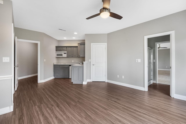 unfurnished living room with a ceiling fan, dark wood-style flooring, and baseboards