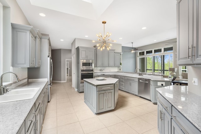 kitchen with stainless steel appliances, a peninsula, gray cabinetry, and a sink