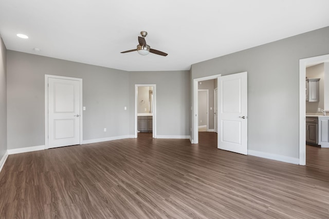 unfurnished bedroom with ceiling fan, connected bathroom, baseboards, and wood finished floors