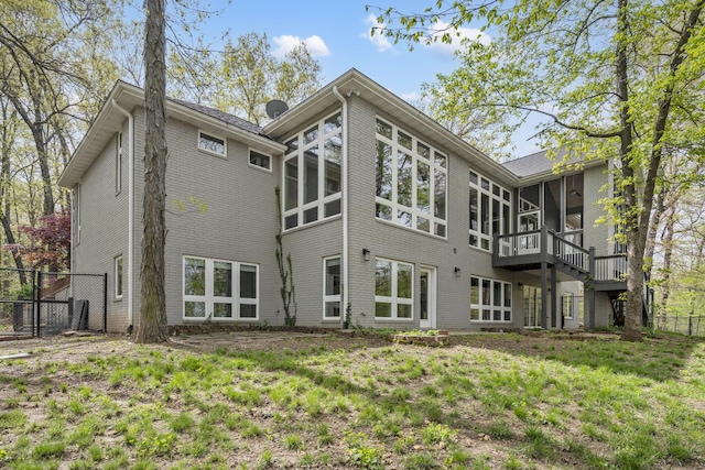 back of property with a sunroom, fence, and brick siding