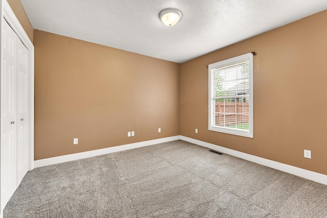 carpeted empty room featuring baseboards and visible vents