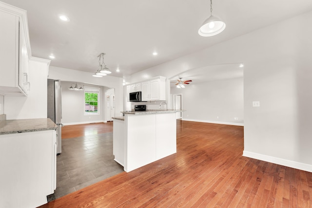 kitchen with a ceiling fan, stainless steel appliances, white cabinets, light wood-type flooring, and decorative light fixtures
