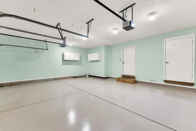 garage with baseboards, visible vents, and a garage door opener