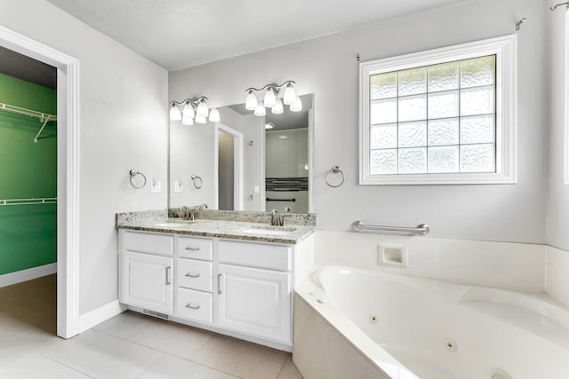 full bath featuring a tub with jets, tile patterned floors, double vanity, and a sink