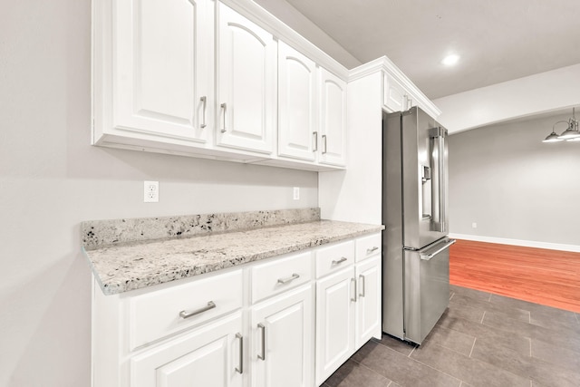 kitchen with high quality fridge, recessed lighting, light stone counters, tile patterned floors, and white cabinets
