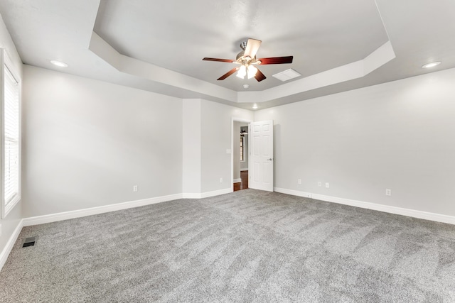 carpeted spare room featuring visible vents, recessed lighting, a ceiling fan, a tray ceiling, and baseboards