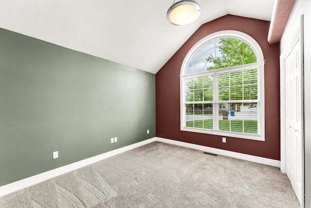 unfurnished room featuring baseboards, carpet floors, and vaulted ceiling