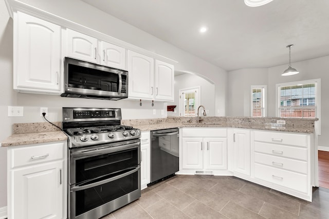kitchen with a peninsula, a sink, stainless steel appliances, visible vents, and light stone counters