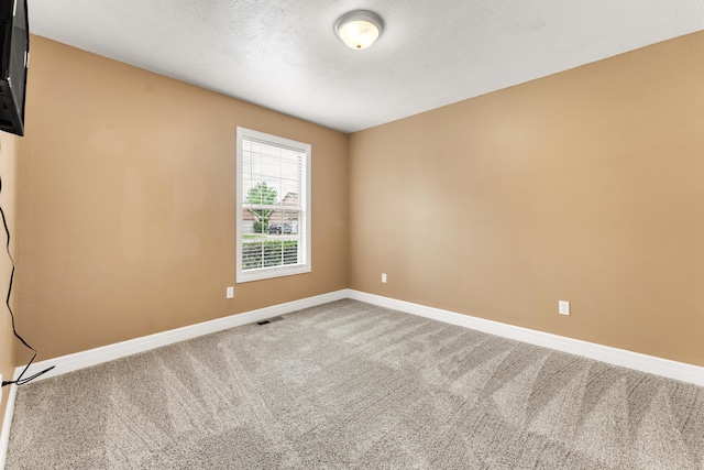 carpeted spare room featuring baseboards and visible vents