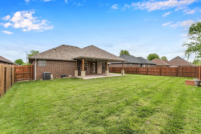 back of property featuring brick siding, a patio, a fenced backyard, a lawn, and central AC unit