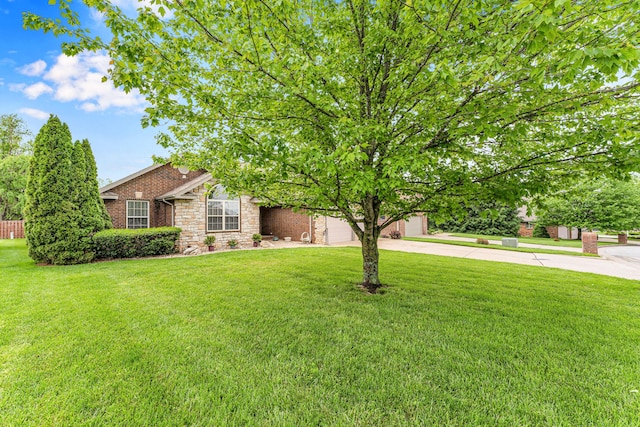 obstructed view of property with driveway, an attached garage, a front yard, and stone siding