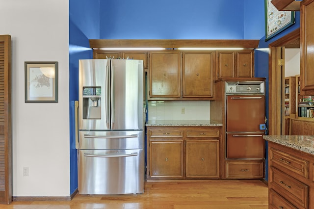 2941 S Versailles Ave, Springfield, MO 65804 - kitchen featuring brown cabinets, light stone counters, stainless steel fridge with ice dispenser, and light wood-type flooring
