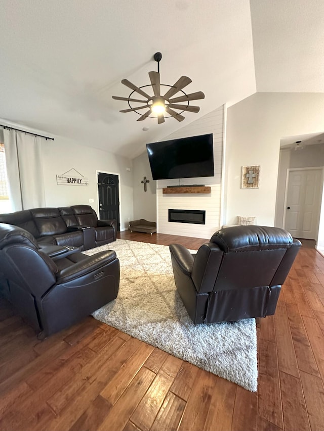 living room with lofted ceiling, a ceiling fan, a glass covered fireplace, and hardwood / wood-style flooring