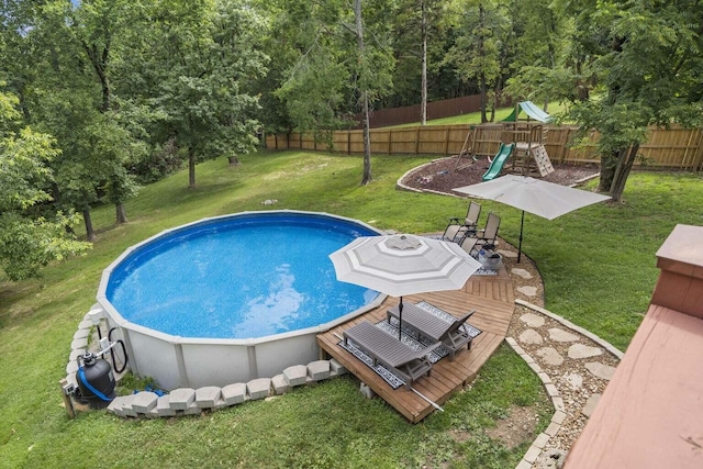 view of pool with a lawn, a fenced in pool, a playground, a deck, and a fenced backyard
