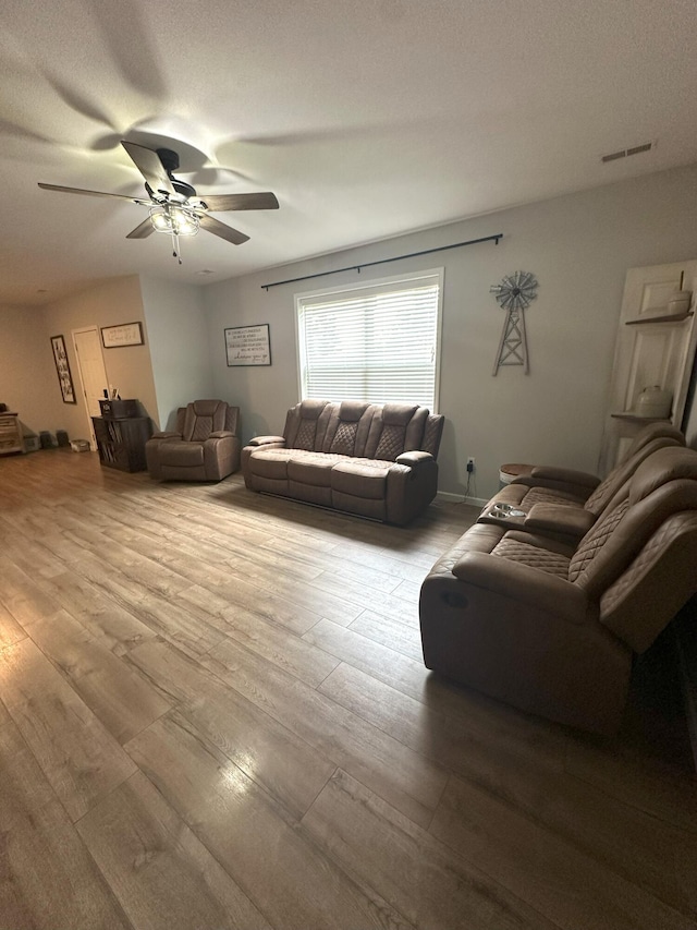 living room featuring a ceiling fan, visible vents, and wood finished floors
