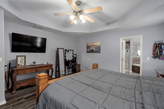 bedroom with wood finished floors, ensuite bath, visible vents, a ceiling fan, and a raised ceiling