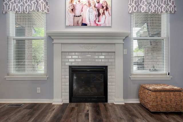 interior details featuring baseboards, a brick fireplace, visible vents, and wood finished floors