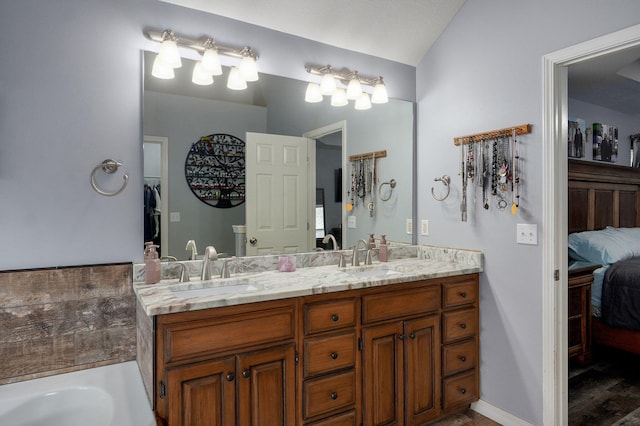 bathroom with double vanity, connected bathroom, vaulted ceiling, and a sink