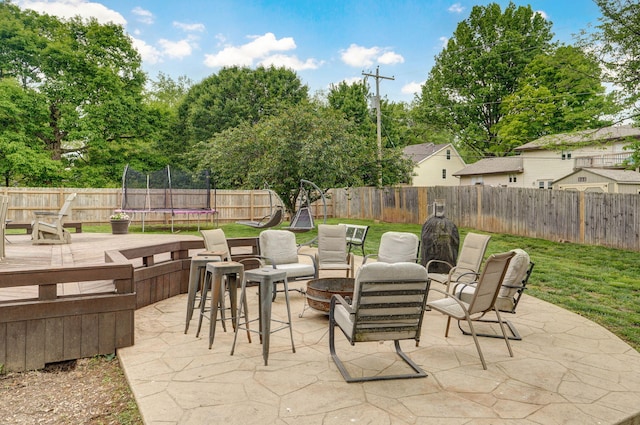 view of patio / terrace featuring an outdoor fire pit, a trampoline, and a fenced backyard