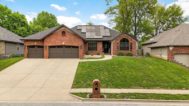 view of front of property featuring concrete driveway, a front lawn, solar panels, brick siding, and roof with shingles
