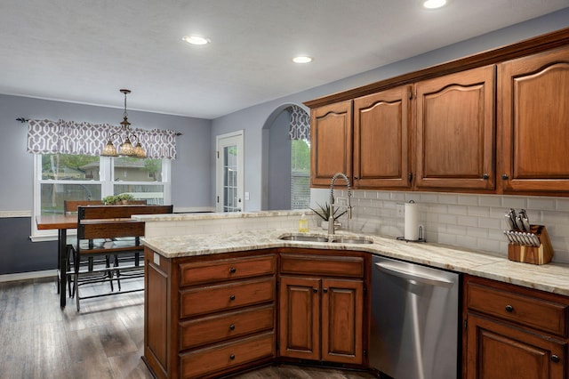 kitchen with a peninsula, a sink, stainless steel dishwasher, arched walkways, and dark wood-style floors