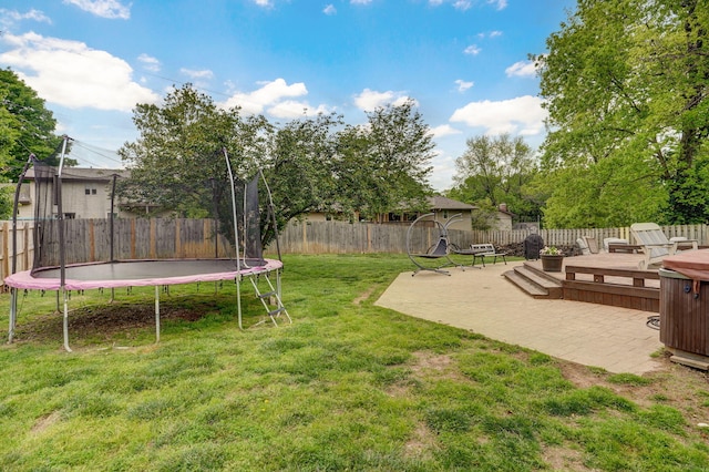view of yard featuring a trampoline, a patio, a deck, and a fenced backyard