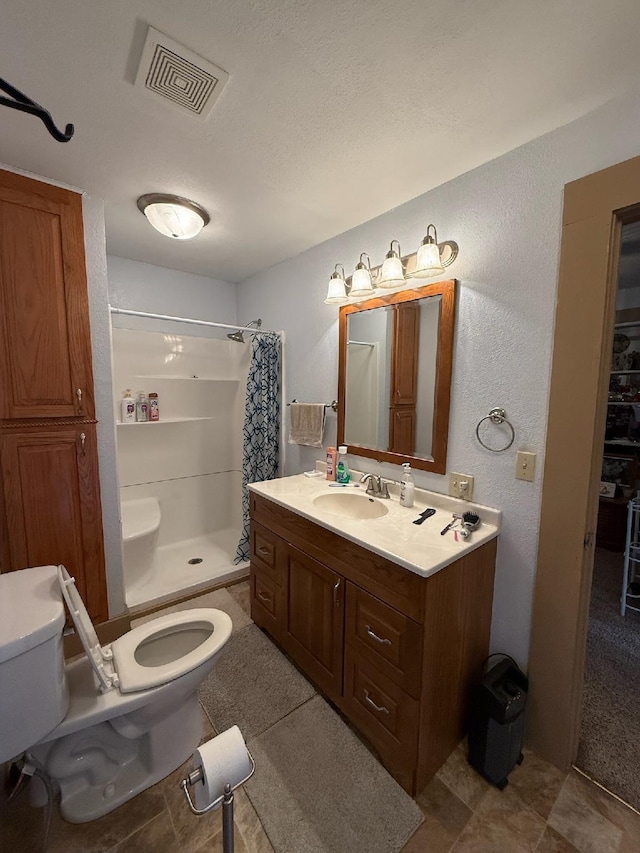 bathroom featuring toilet, a stall shower, visible vents, a textured wall, and vanity