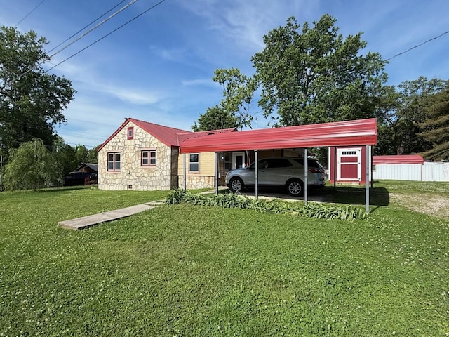 view of front facade with stone siding, fence, metal roof, a carport, and a front yard