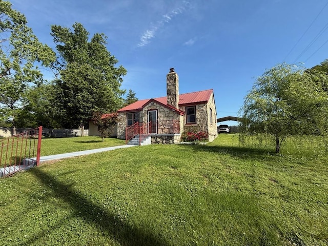 bungalow-style home featuring fence, stone siding, a front yard, metal roof, and a chimney