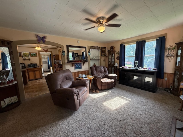 living area with arched walkways, ceiling fan, and carpet