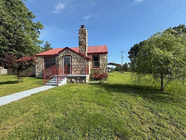 bungalow-style home with metal roof, a chimney, a front lawn, and stone siding