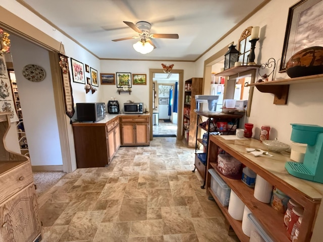 kitchen featuring a ceiling fan, stone finish floor, stainless steel microwave, open shelves, and light countertops