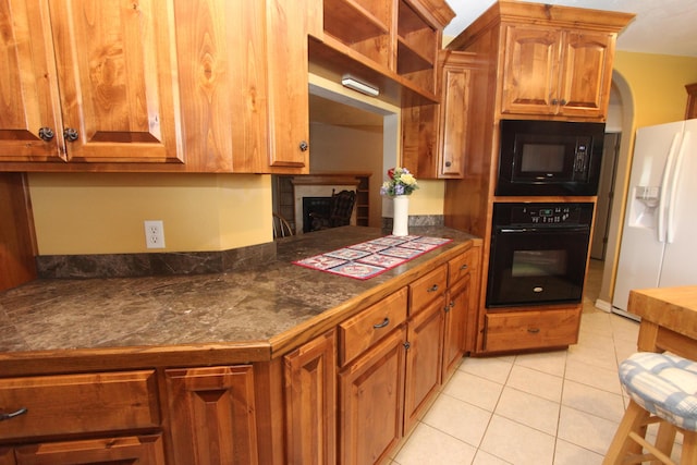 289 Frog Pond Rd, Seymour, MO 65746 - kitchen with brown cabinetry, black appliances, a fireplace, light tile patterned floors, and dark countertops