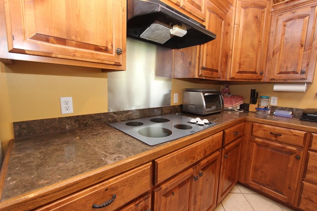 289 Frog Pond Rd, Seymour, MO 65746 - kitchen with brown cabinets, a toaster, under cabinet range hood, stovetop, and dark countertops