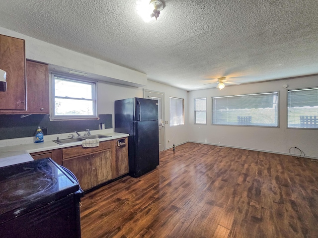 25454 Tulip Pl, Urbana, MO 65767 - kitchen with a sink, a textured ceiling, dark wood-style flooring, black appliances, and light countertops